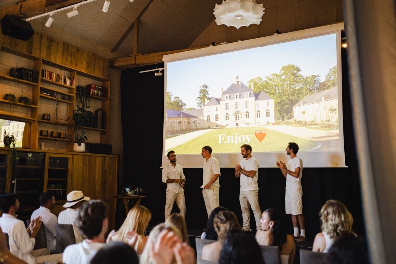 Men on stage present to a clapping audience in a corporate event venue