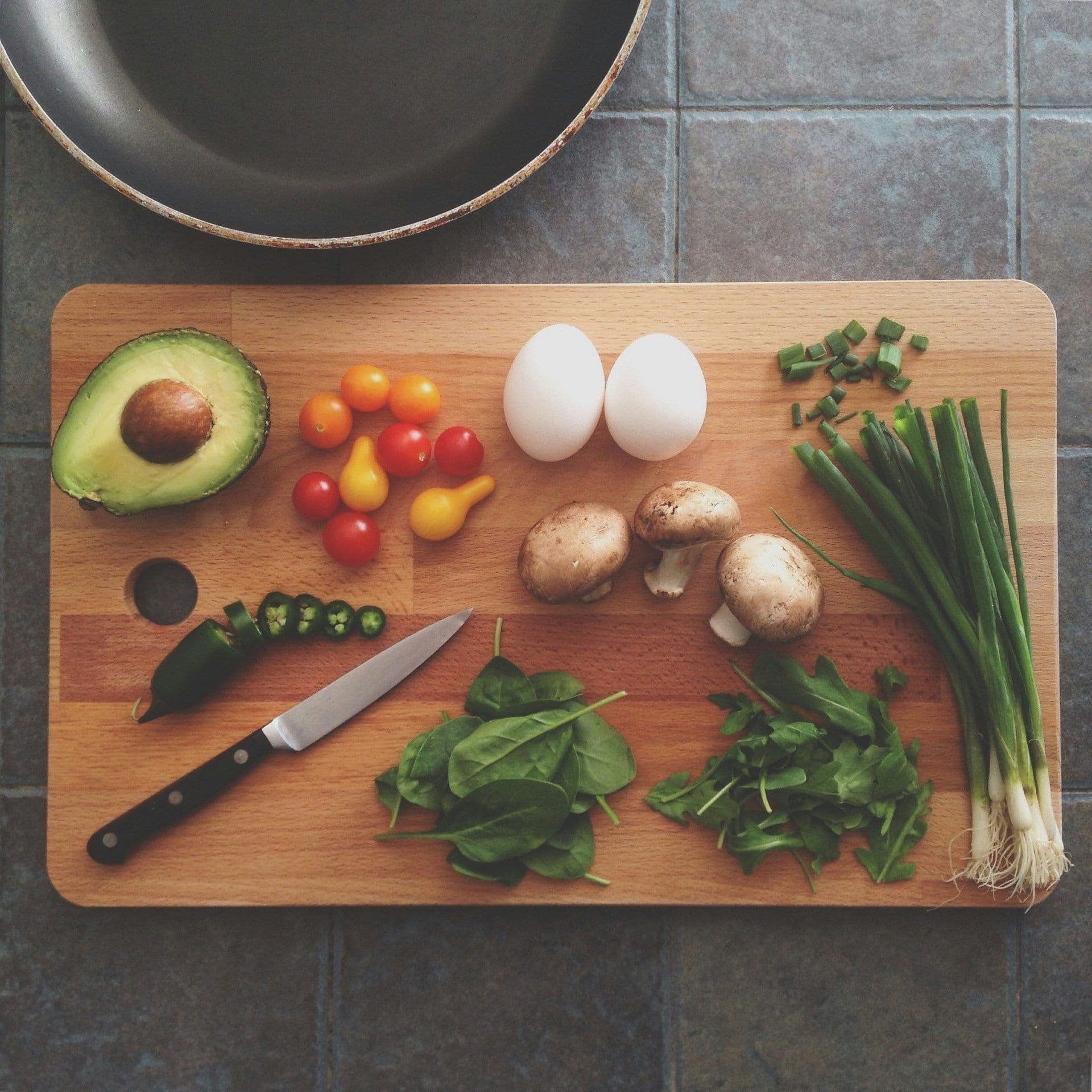 Fresh ingredients like avocado, eggs, and vegetables on a cutting board