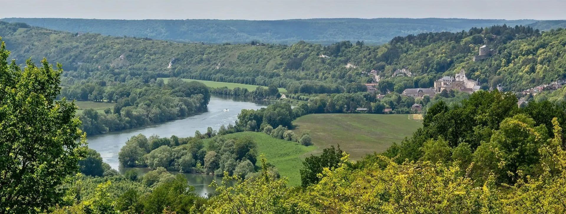 Scenic river valley with a historic castle and town, ideal for a corporate retreat in Île-de-France, France.