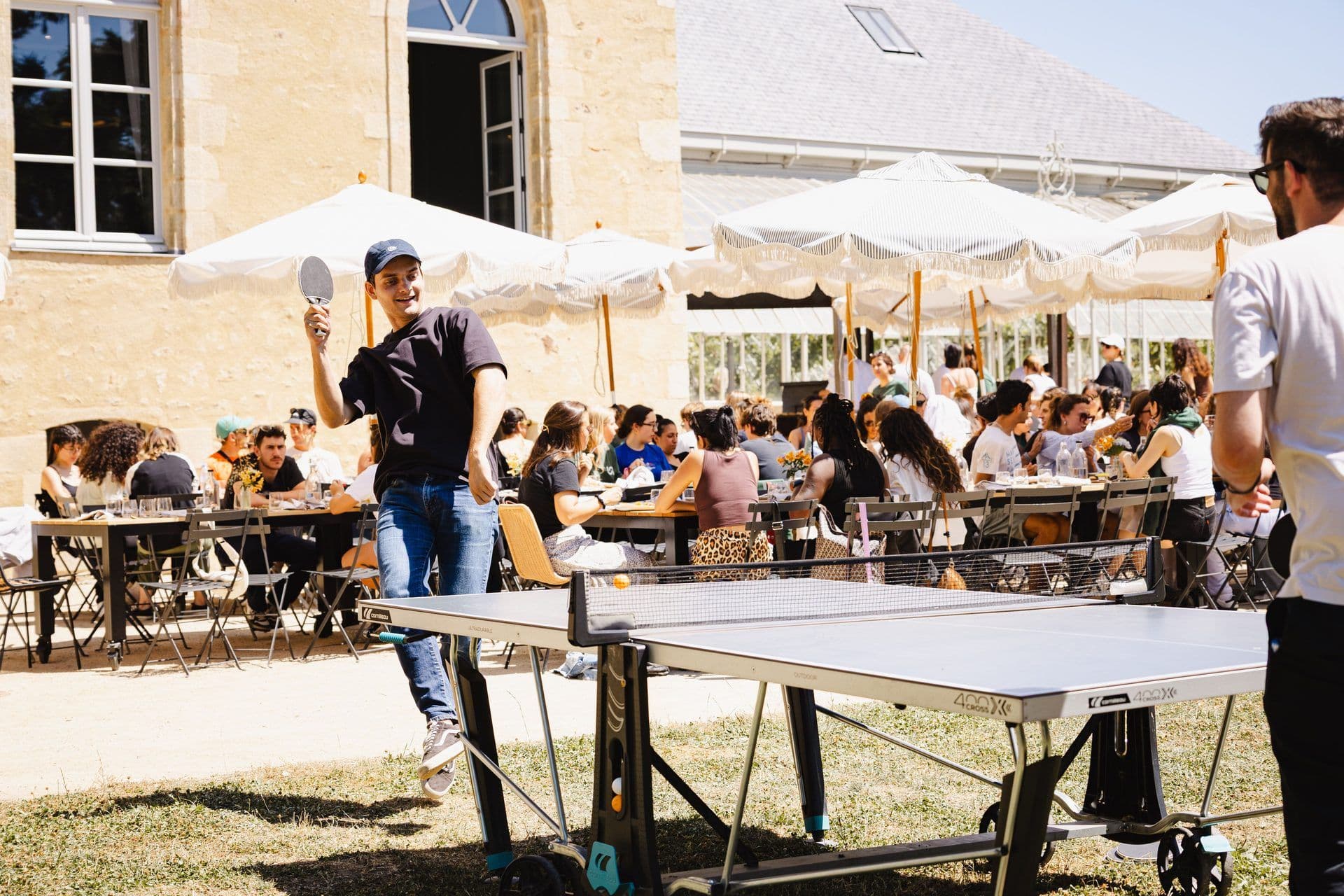 Employees enjoy an outdoor team building activity with table tennis and a business lunch at a historic venue.