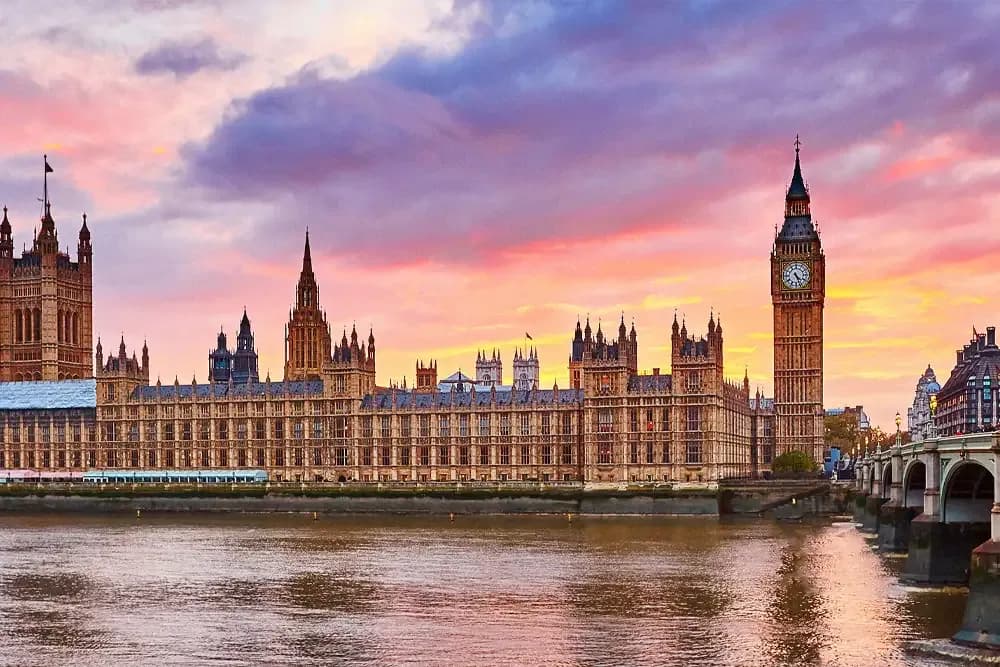 The iconic Houses of Parliament and Big Ben in London at sunset, overlooking the River Thames.