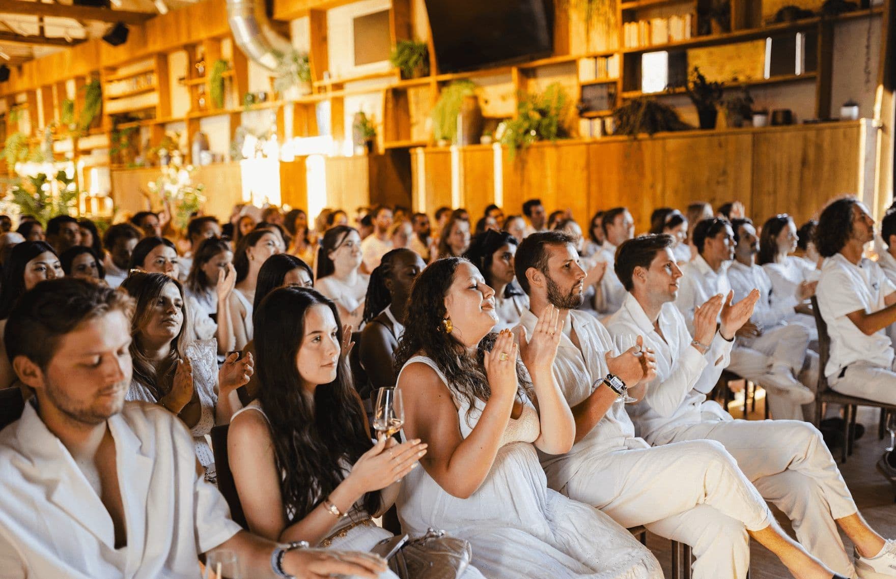 Attendees clap during a corporate seminar or company kickoff in a warm, unique event venue.