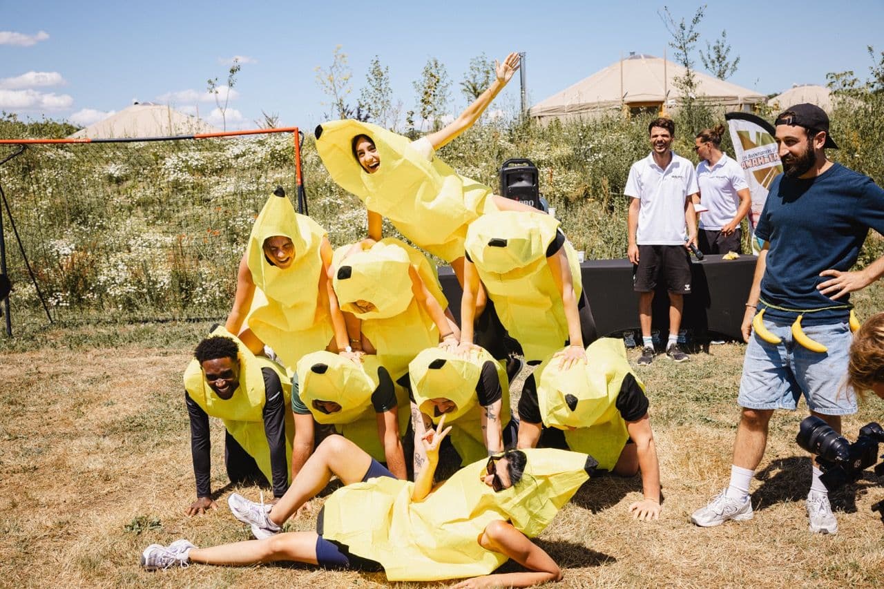 Colleagues in banana costumes form a human pyramid during an outdoor team building event.