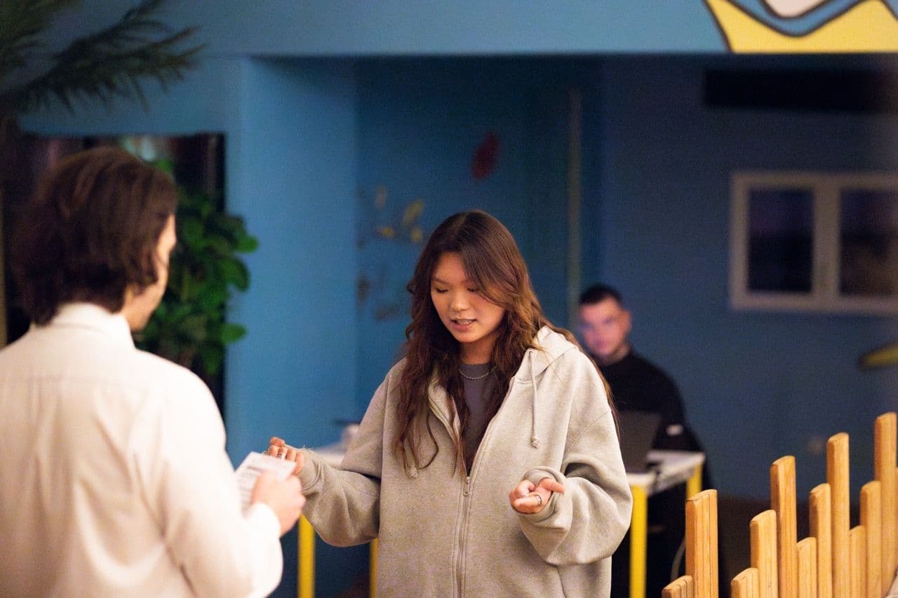 A woman receives materials from a man during a corporate workshop in a modern event space.