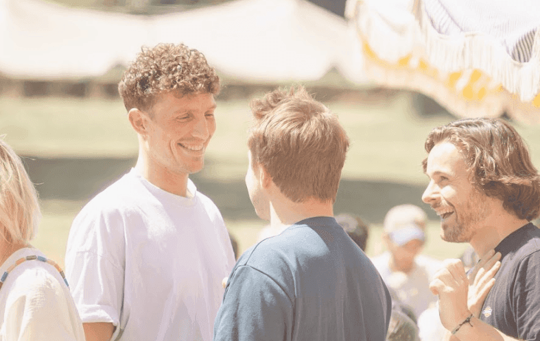 Smiling colleagues networking at an outdoor corporate team building event on a sunny day.