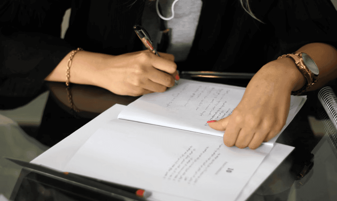 Close-up of hands writing notes on a document, likely planning for a corporate event or workshop.
