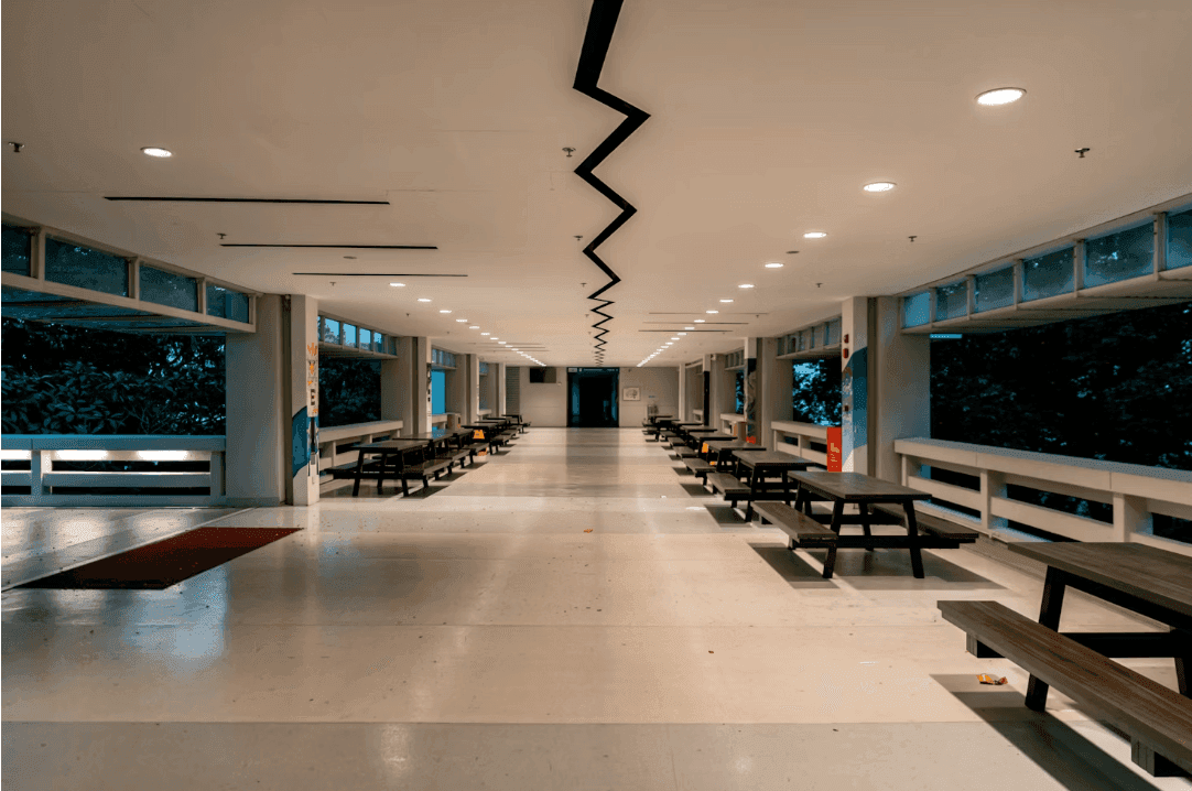 Spacious corporate event venue featuring picnic tables, large windows overlooking trees