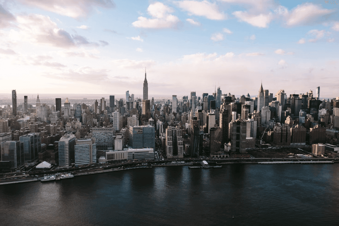 Panoramic view of the New York City skyline with the Empire State Building and a waterfront.