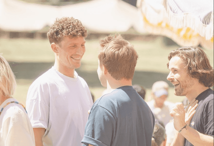 Smiling colleagues networking at a sunny outdoor corporate event or company away day.