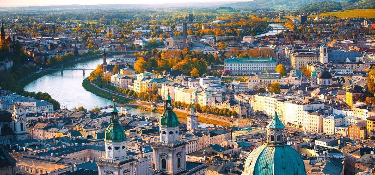 Aerial view of Salzburg, Austria, showcasing the Salzach river winding through historic buildings and autumn