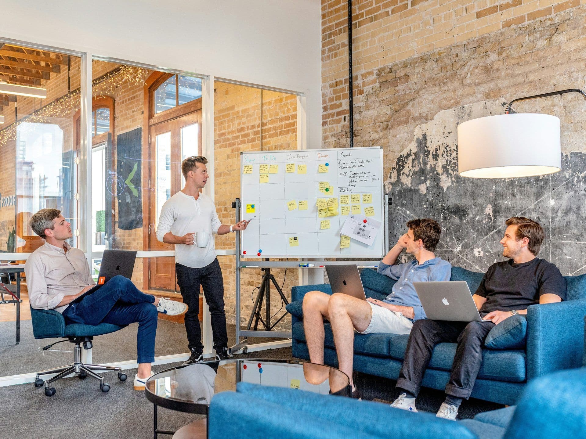 A team conducts a workshop in a unique corporate event venue with exposed brick and glass partitions.