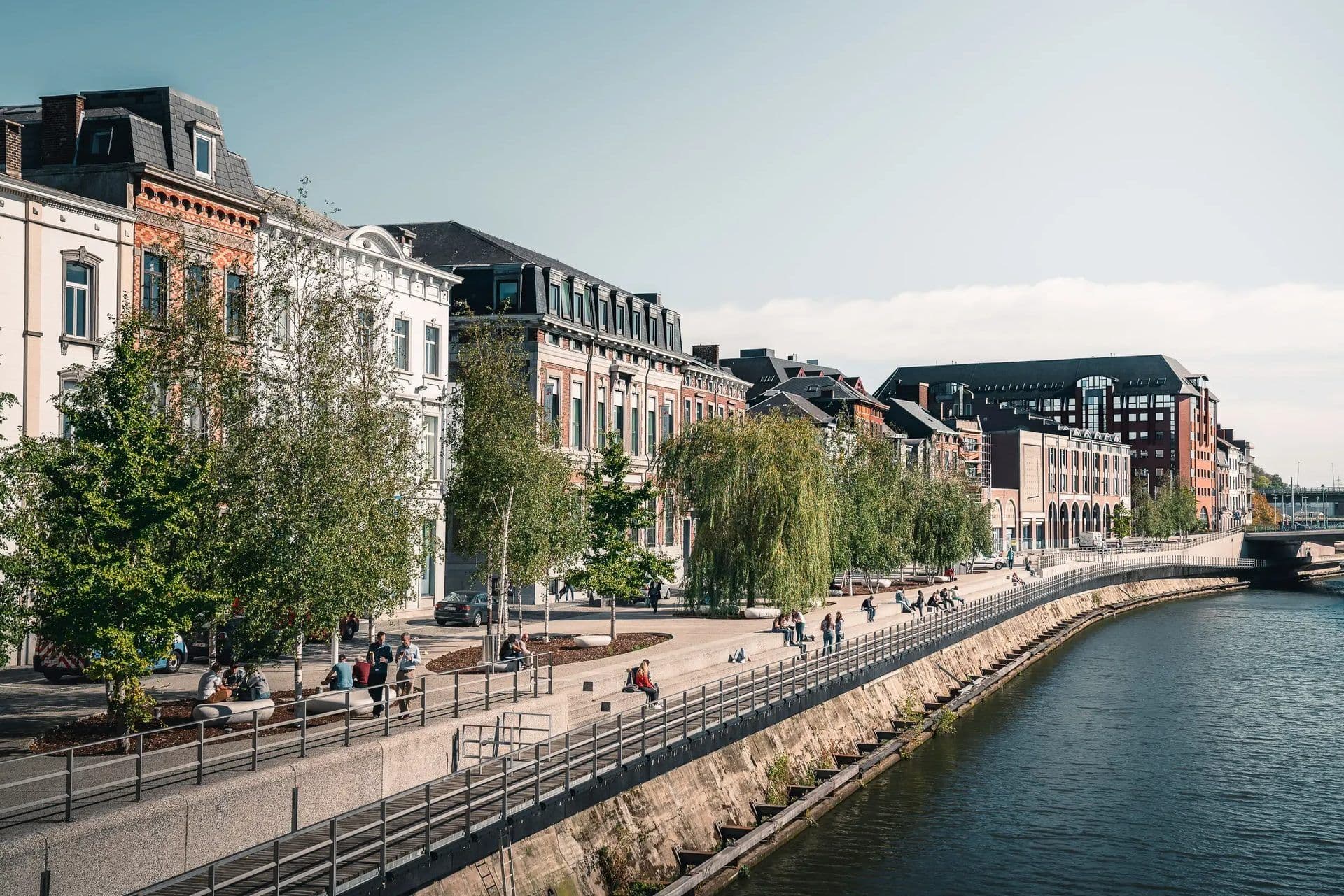 A bustling waterfront promenade in Charleroi, Belgium, with classic European architecture and an outdoor