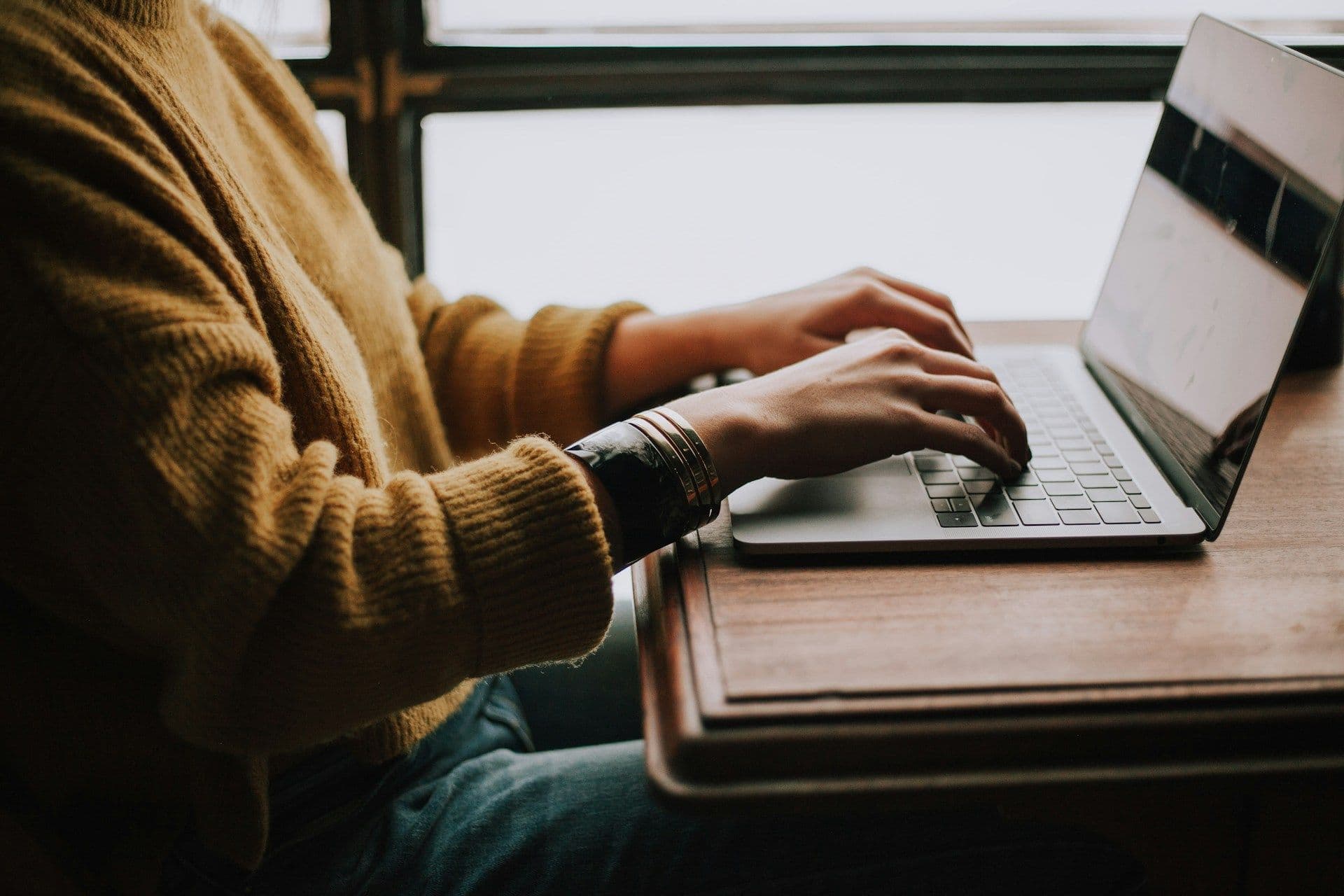 Hands typing on a laptop, researching and booking corporate event venues for enterprise clients.