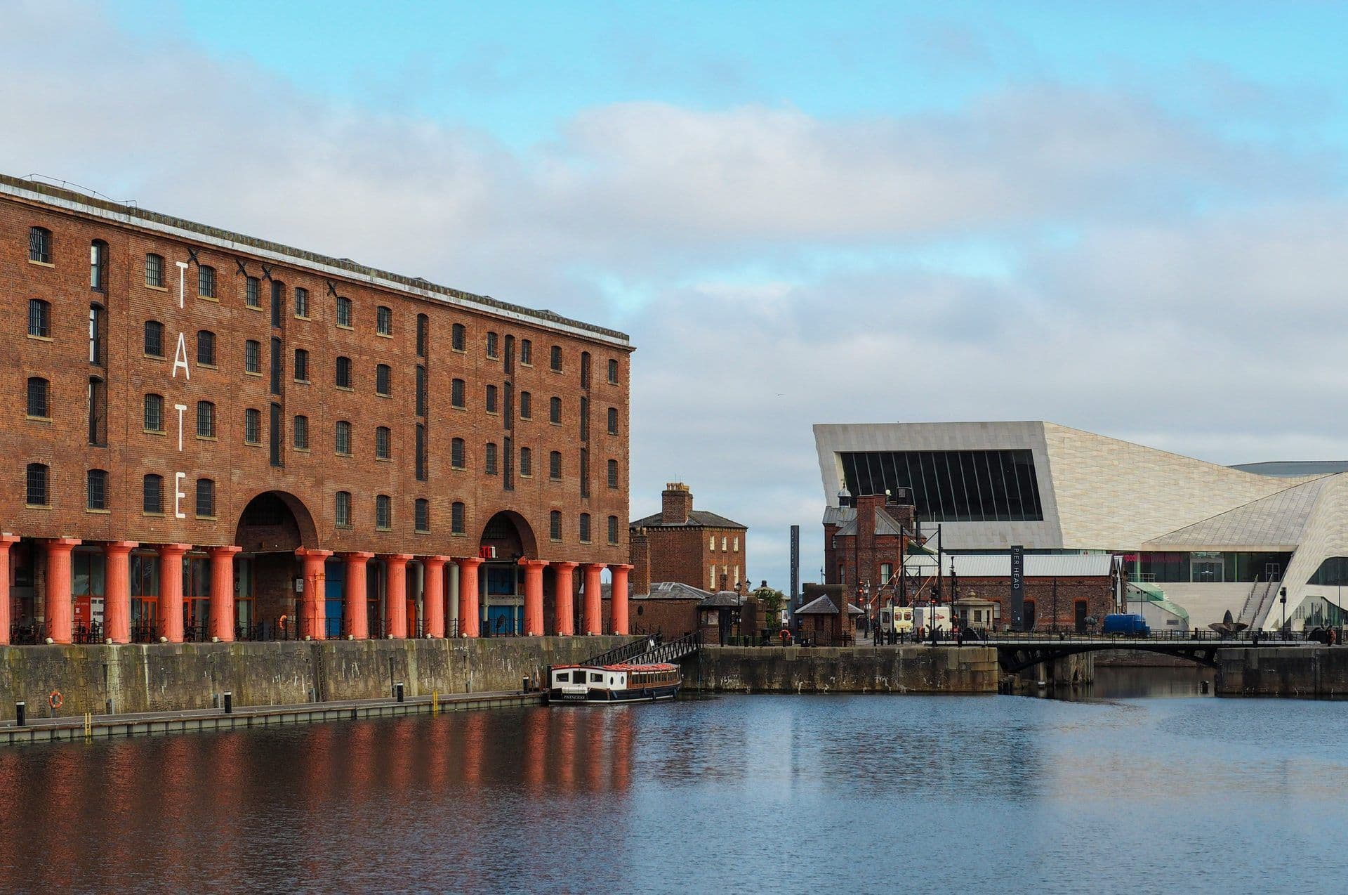 Historic brick Tate Liverpool and modern museum buildings overlook Albert Dock in Liverpool, UK.