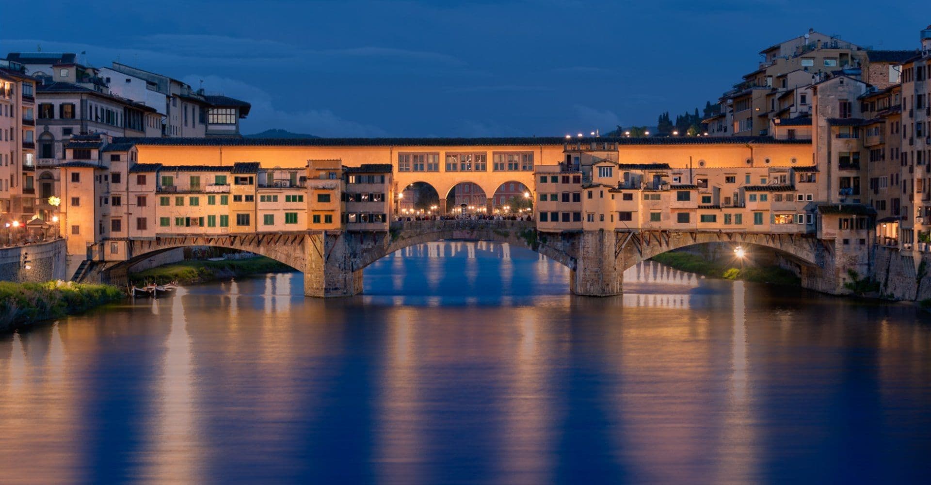 Ponte Vecchio, a unique historic venue in Florence, Italy, illuminated at night over the Arno River.