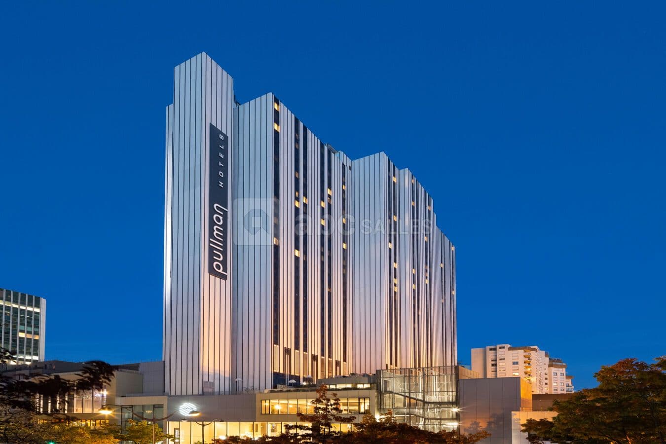 The illuminated Pullman Paris Montparnasse hotel, a modern corporate event venue for large groups.