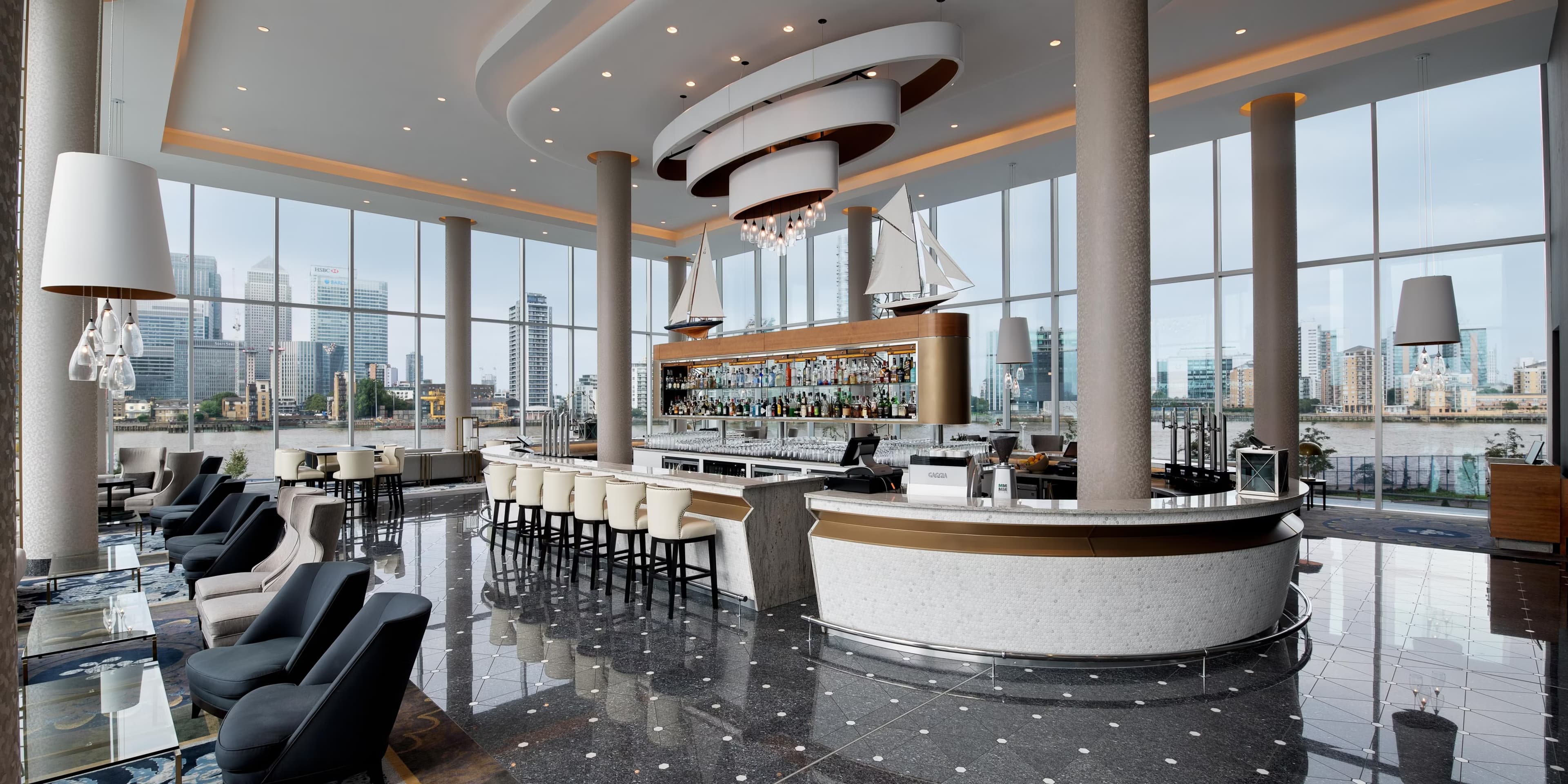 Modern London waterfront event venue with a sophisticated bar, lounge seating, and panoramic city views.