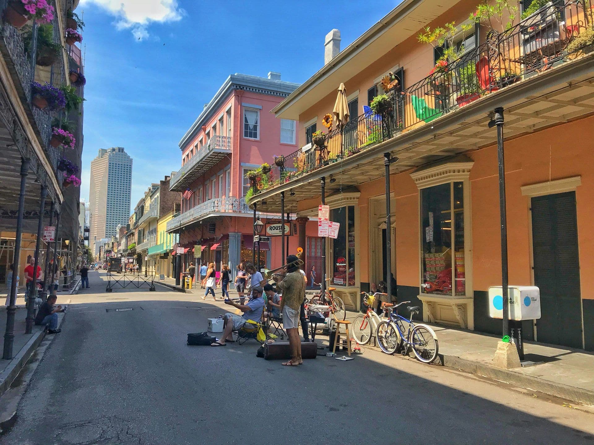 Historic French Quarter street in New Orleans with colorful buildings, iron balconies, and street performers.