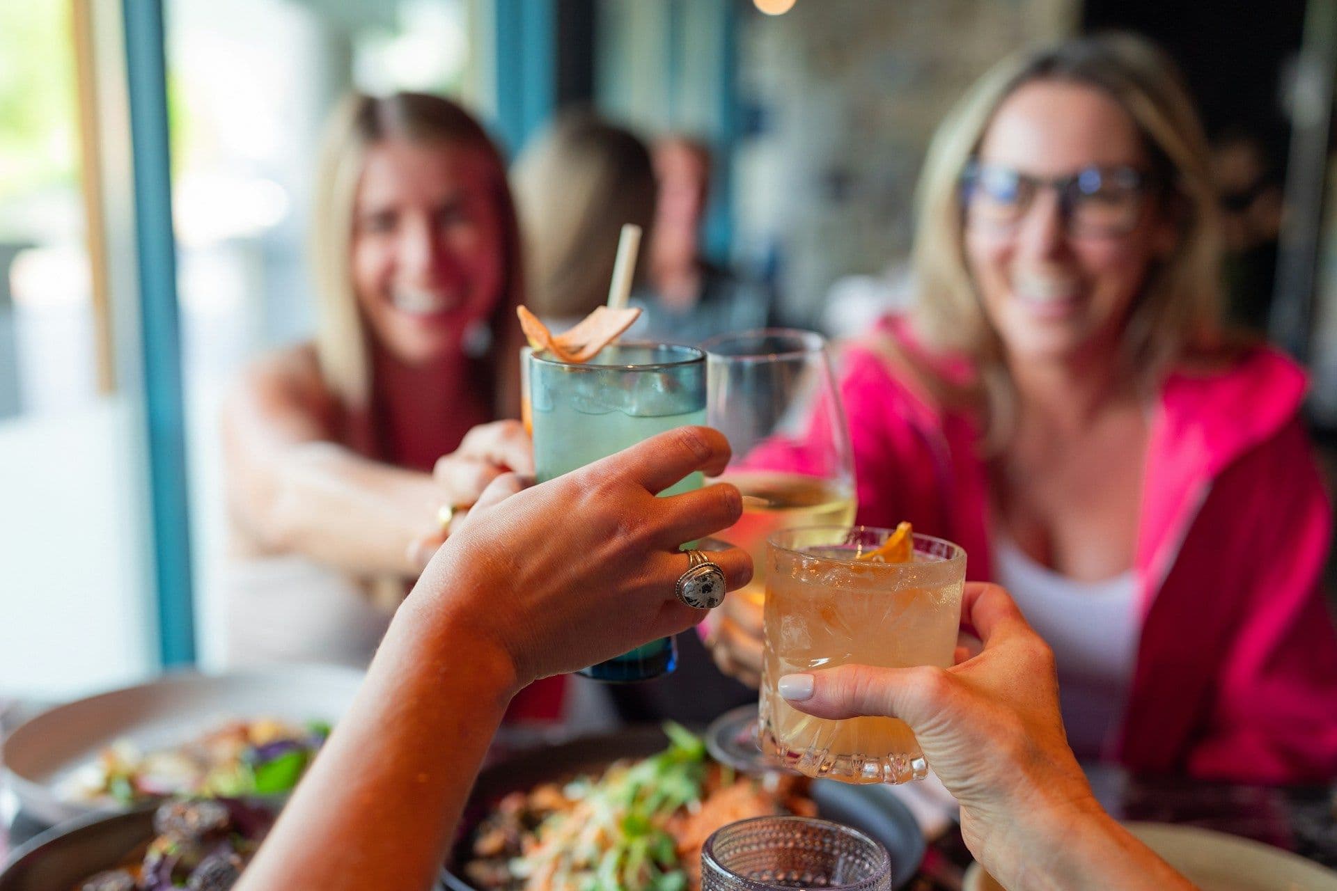 Smiling colleagues toast with cocktails and wine at a corporate dinner or networking event.