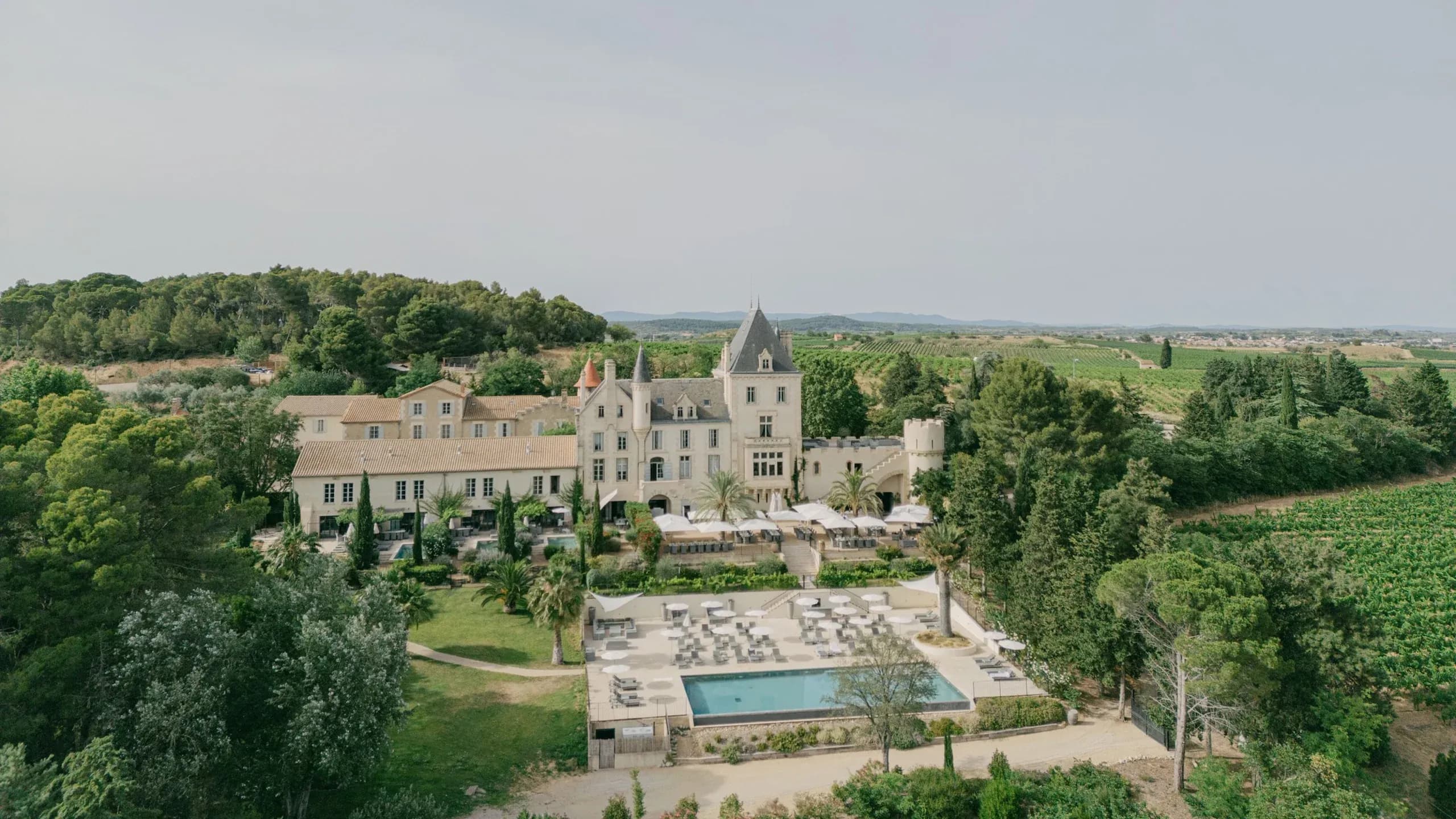 Aerial view of a historic chateau corporate retreat venue with a pool, terraces, and vineyards.