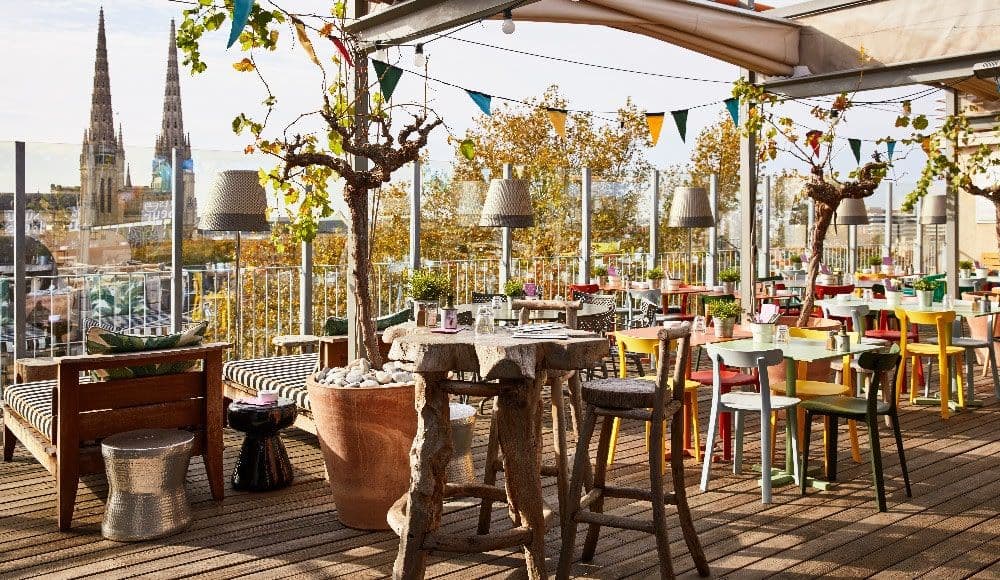 Colorful rooftop terrace event space with diverse seating and city views of Bordeaux, France.