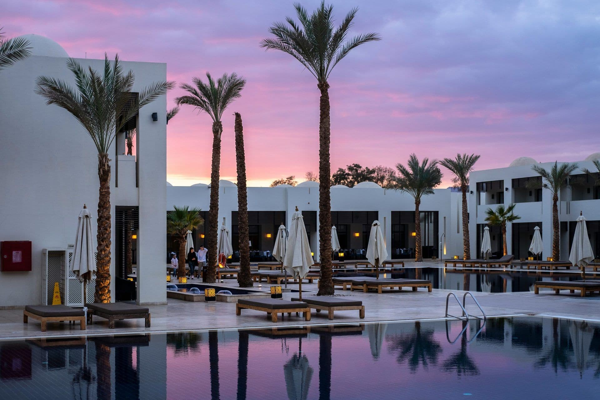 Stunning resort pool and outdoor event space at dusk, featuring palm trees and modern architecture.