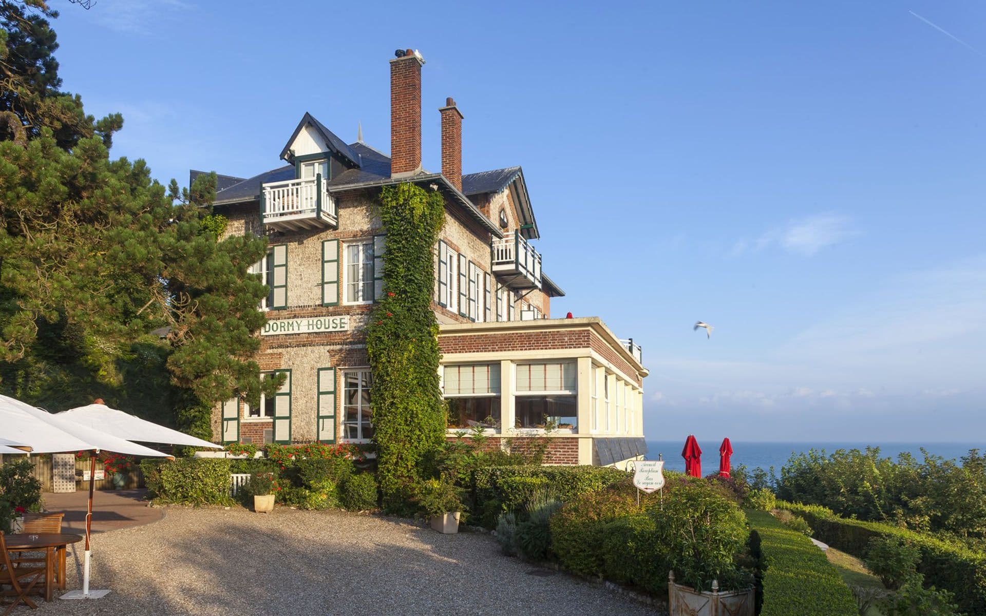 Historic Dormy House, a waterfront corporate event venue in Etretat, France, with outdoor seating.
