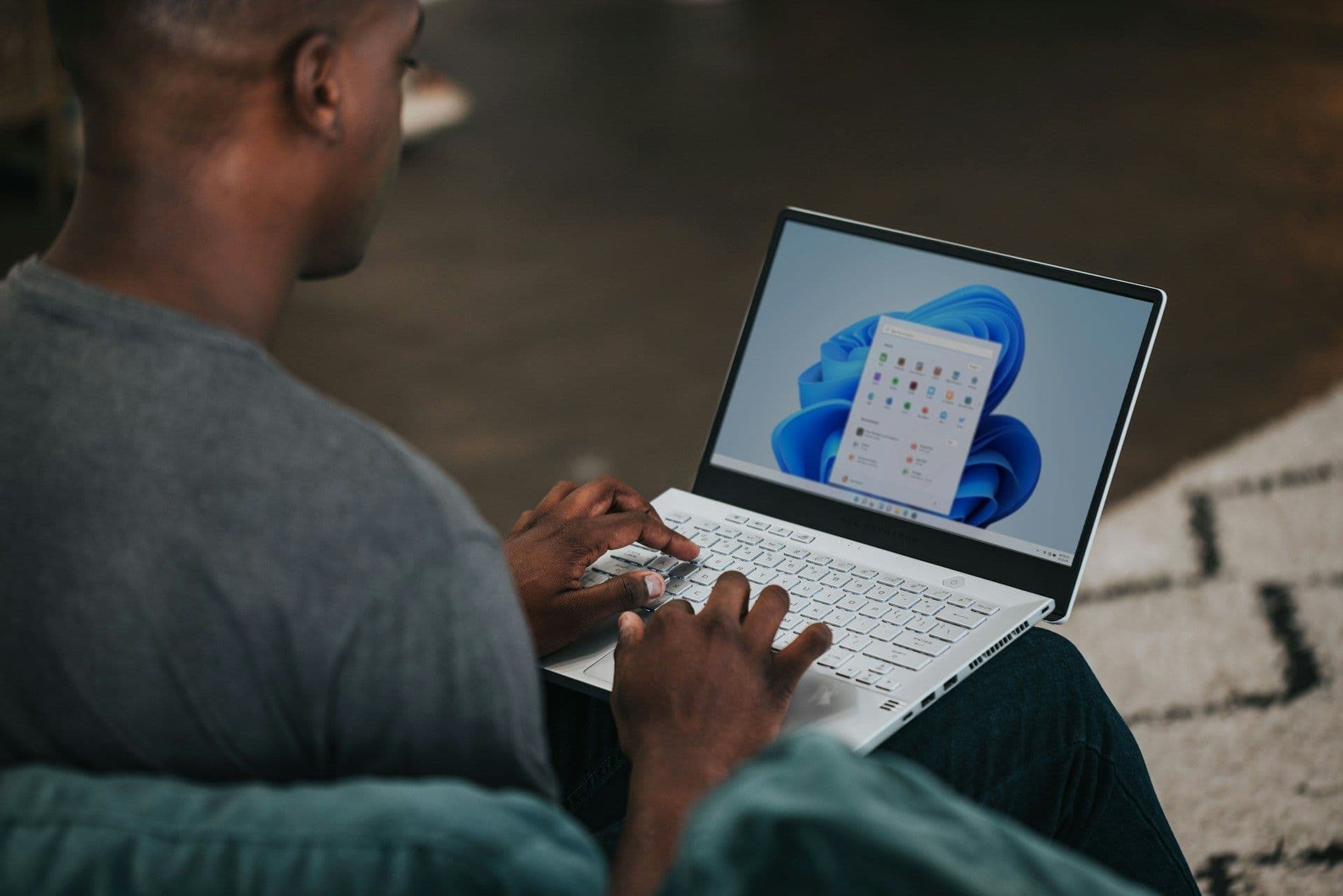 An individual types on a white laptop, researching and planning corporate events or venue bookings.